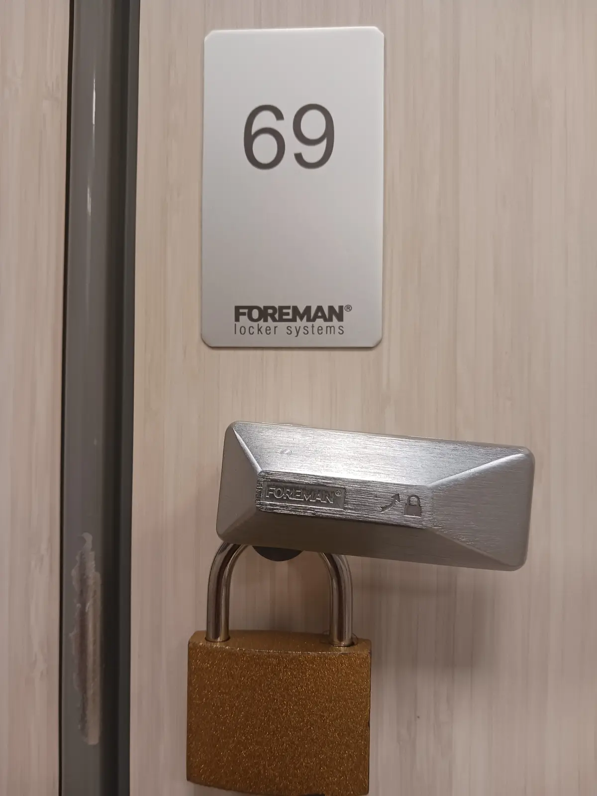 A close-up photo shows a locker door with a white label reading '69' and 'FOREMAN locker systems' below it. A large…