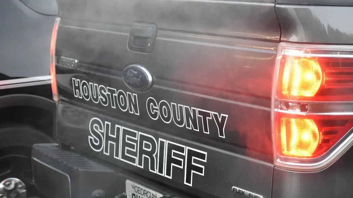 A close-up of the rear of a black Ford pickup truck with 'HOUSTON COUNTY SHERIFF' written in large white letters. The…