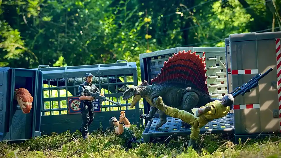 A staged scene with toy action figures and dinosaurs in outdoor crates, one figure is being thrown by a dinosaur while…
