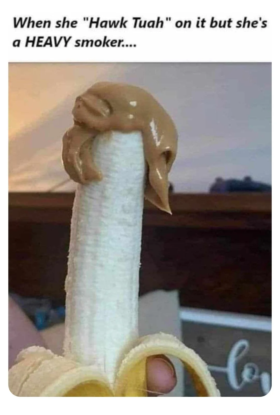 A close-up photo shows a peeled banana with a large, messy dollop of peanut butter clinging to its top, resembling a heavy…