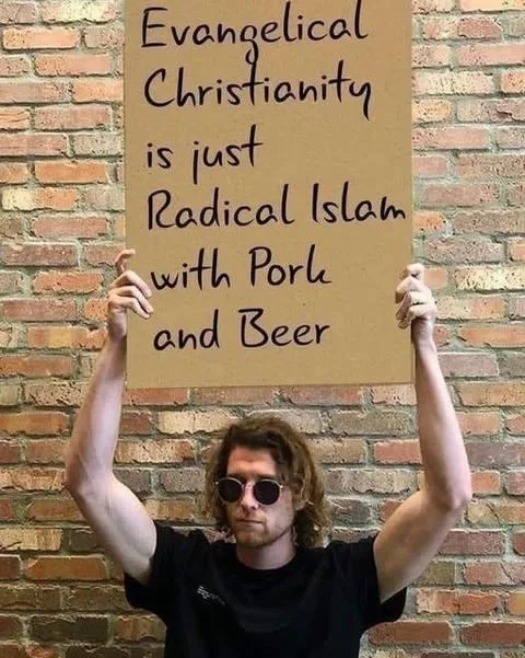 A man with curly hair and sunglasses holds up a cardboard sign against a brick wall. The sign reads 'Evangelical…