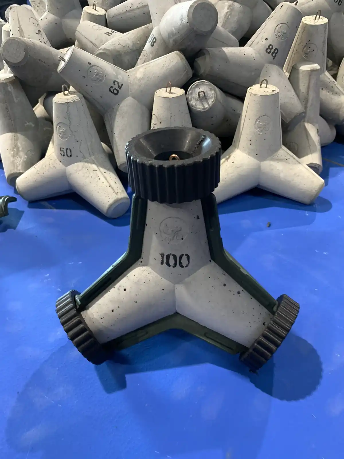 A close-up photo shows a pile of gray concrete weights with numbers like 50, 62, and 88, and one prominently displayed…