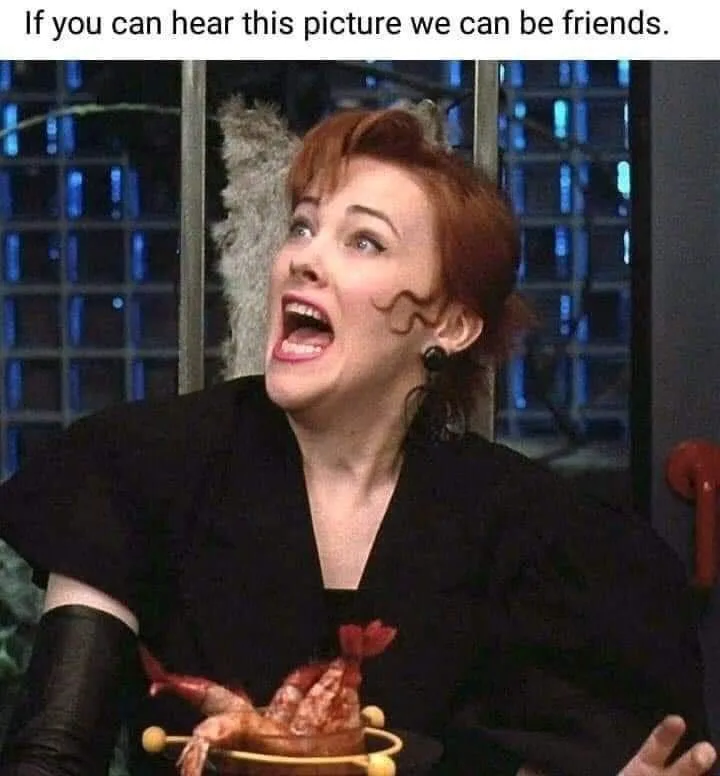 A woman with red hair and black clothing is shown with her mouth wide open in a scream, holding a dish with what appears to…
