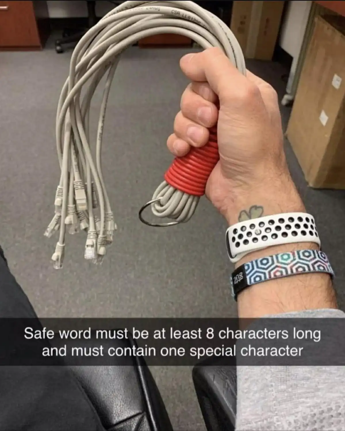 A person's hand grips a bundle of Ethernet cables, which are coiled and secured with a red rubber band, resembling a…