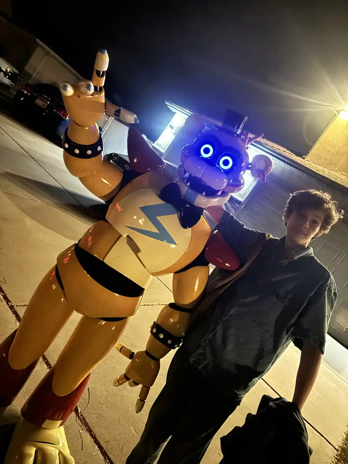 A person stands beside a large animatronic character resembling Freddy Fazbear from Five Nights at Freddy's, which has…