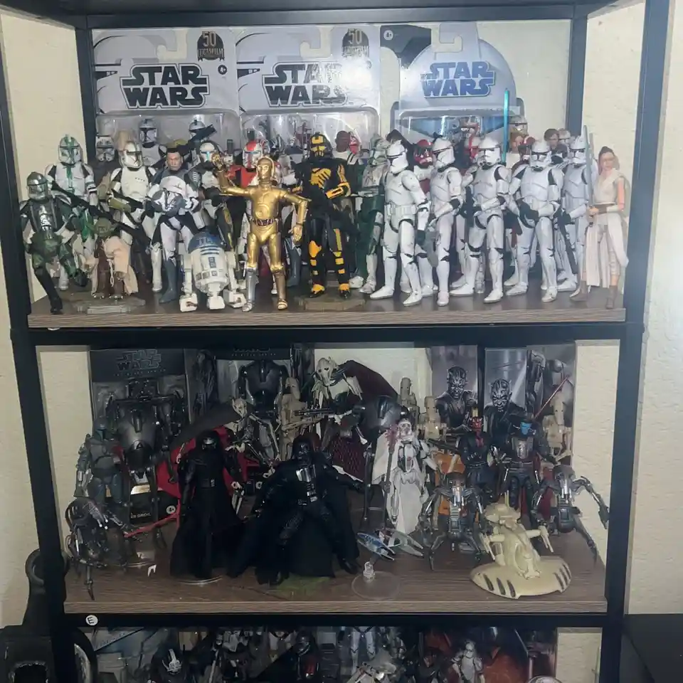 A two-tiered display shelf is packed with numerous Star Wars action figures, including Stormtroopers, Darth Vader, C-3PO…