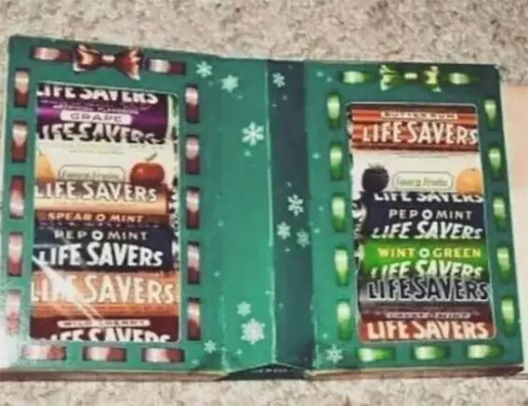 An open, green, holiday-themed Life Savers candy box displays multiple flavor labels on both sides, including Grape, Apple…