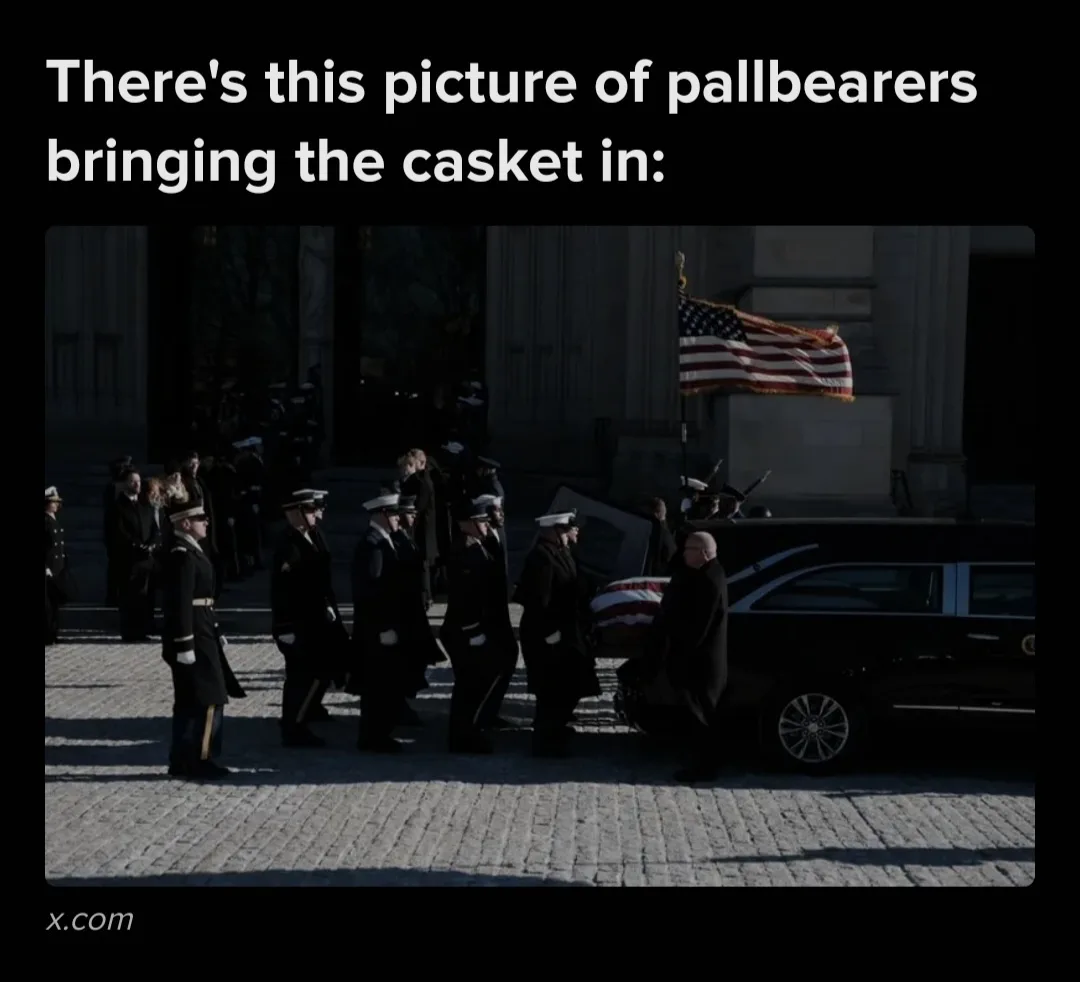 A solemn, sunlit photo shows uniformed military pallbearers carrying a casket draped with an American flag into a large…
