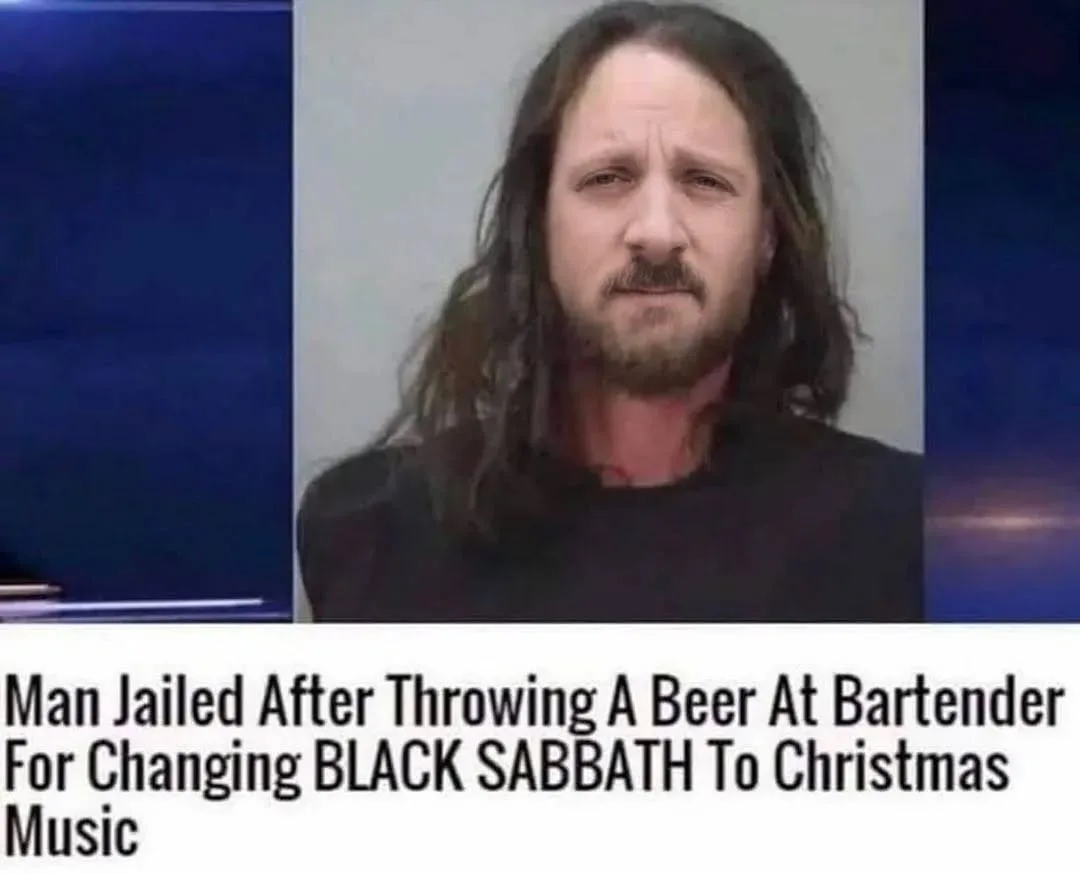 A mugshot-style photo of a man with long dark hair and a beard, wearing a black shirt, is overlaid with bold text stating…