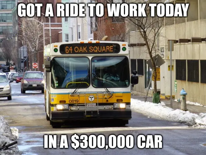 A yellow and white public transit bus, route 64 Oak Square, drives down a snowy city street with cars parked along the side…
