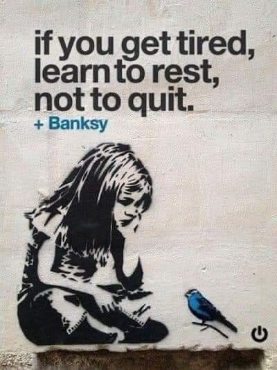 A stencil graffiti artwork shows a woman sitting and resting while a small blue bird stands beside her. The text overlaid…