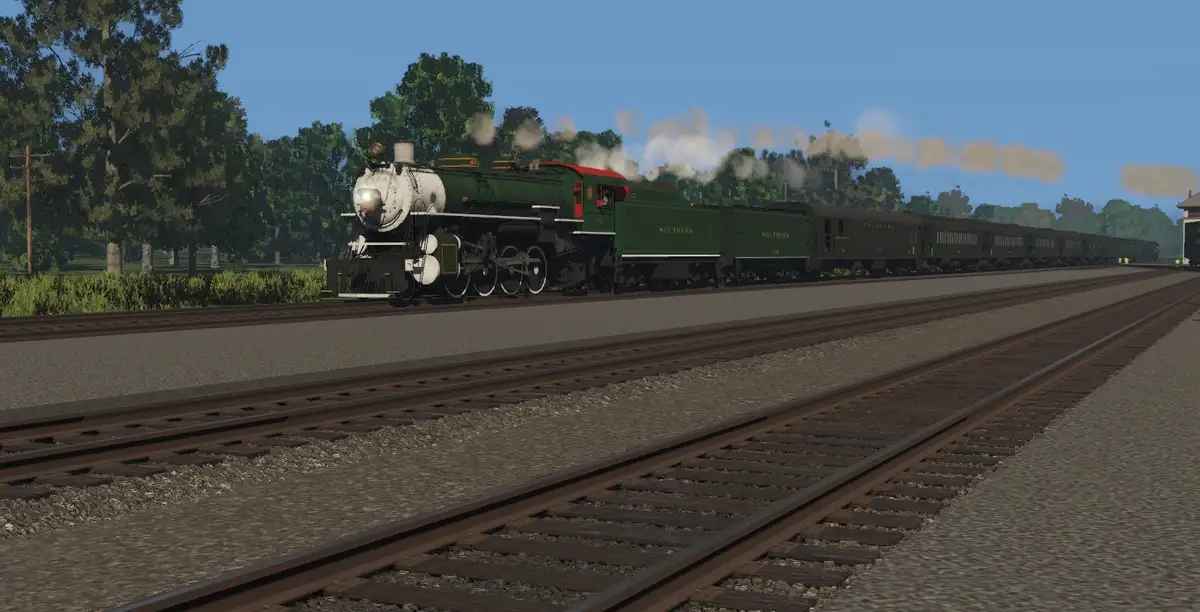 A green steam locomotive with 'SOUTHERN' written on its side pulls a long train along tracks through a wooded area under a…