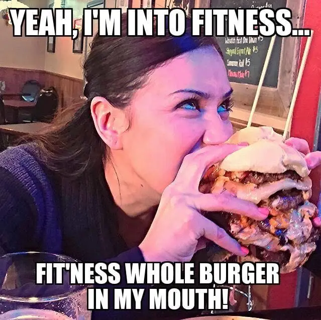 A woman with blue-tinted eyes is shown taking a large bite out of an enormous, multi-layered burger with cheese and sauce…