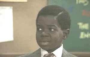 A six-panel image sequence shows a young Black boy in a school setting, wearing a suit and tie, with a green chalkboard…