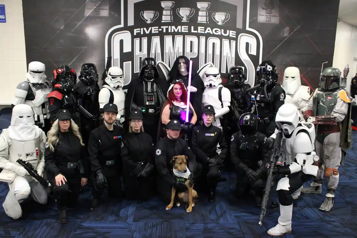 A group of people dressed as Star Wars characters, including Darth Vader, Stormtroopers, and Boba Fett, pose for a photo in…