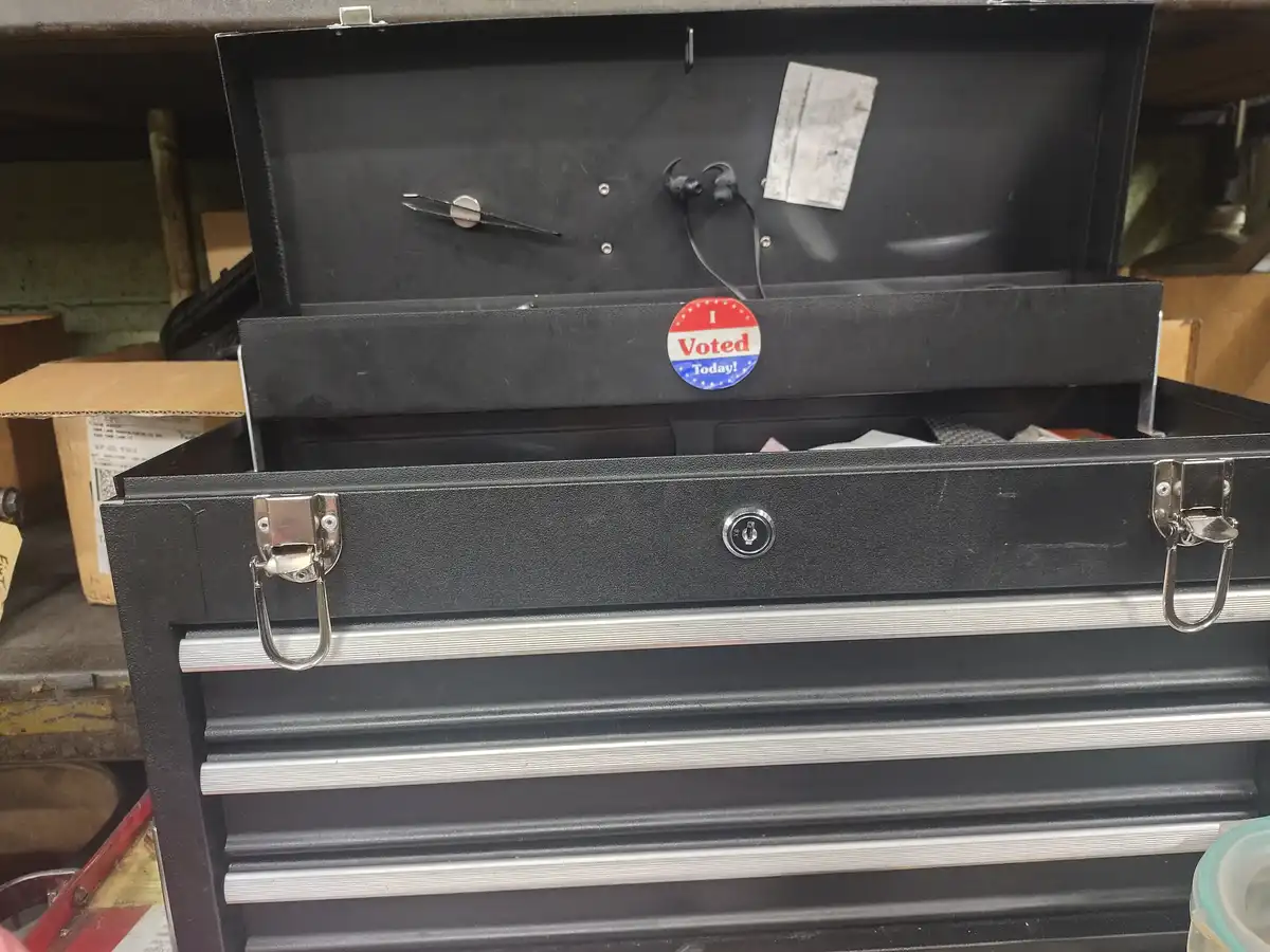 A black metal toolbox with multiple drawers and silver handles is open, revealing a red, white, and blue 'I Voted Today!'…