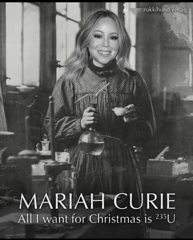 A black-and-white image shows Mariah Carey smiling while holding a flask and a small dish in a laboratory setting. The text…