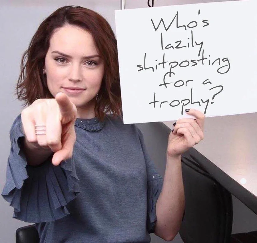 A woman with brown hair and a blue ruffled shirt points directly at the viewer while holding a white sign with handwritten…