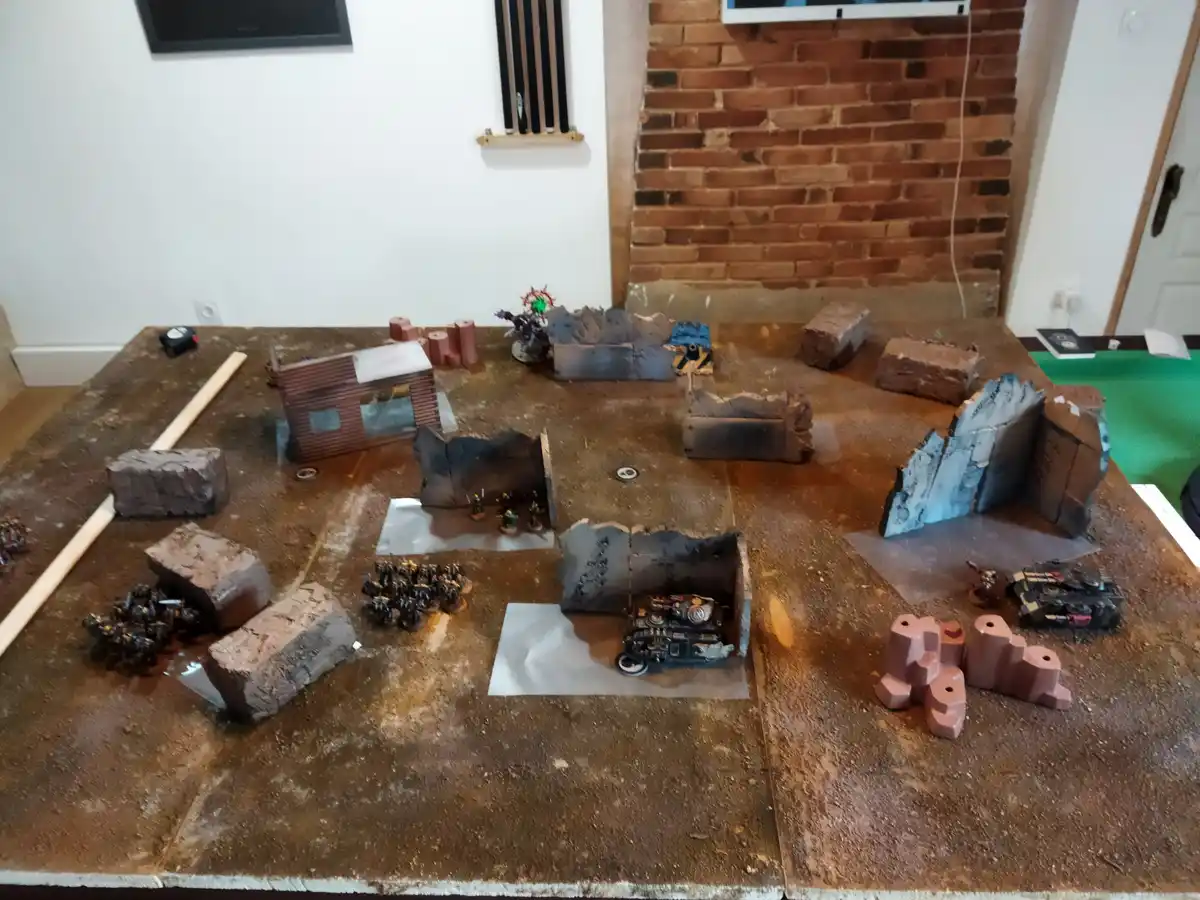 A tabletop wargaming setup with miniature figures and terrain pieces on a brown surface, overlaid with the text 'i'm not a…