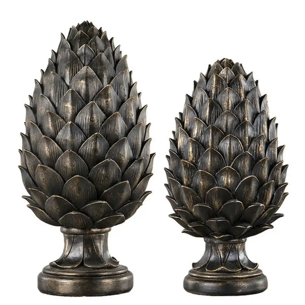 Two ornamental, bronze-finished pinecone sculptures stand side by side against a white background. Each has a detailed…