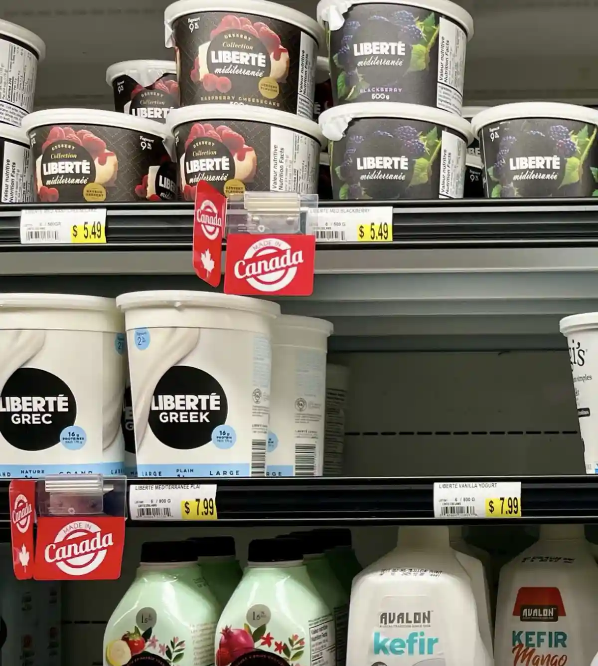 A grocery store shelf displays various Liberté brand yogurt products, including Mediterranean flavors and Greek yogurt, with…