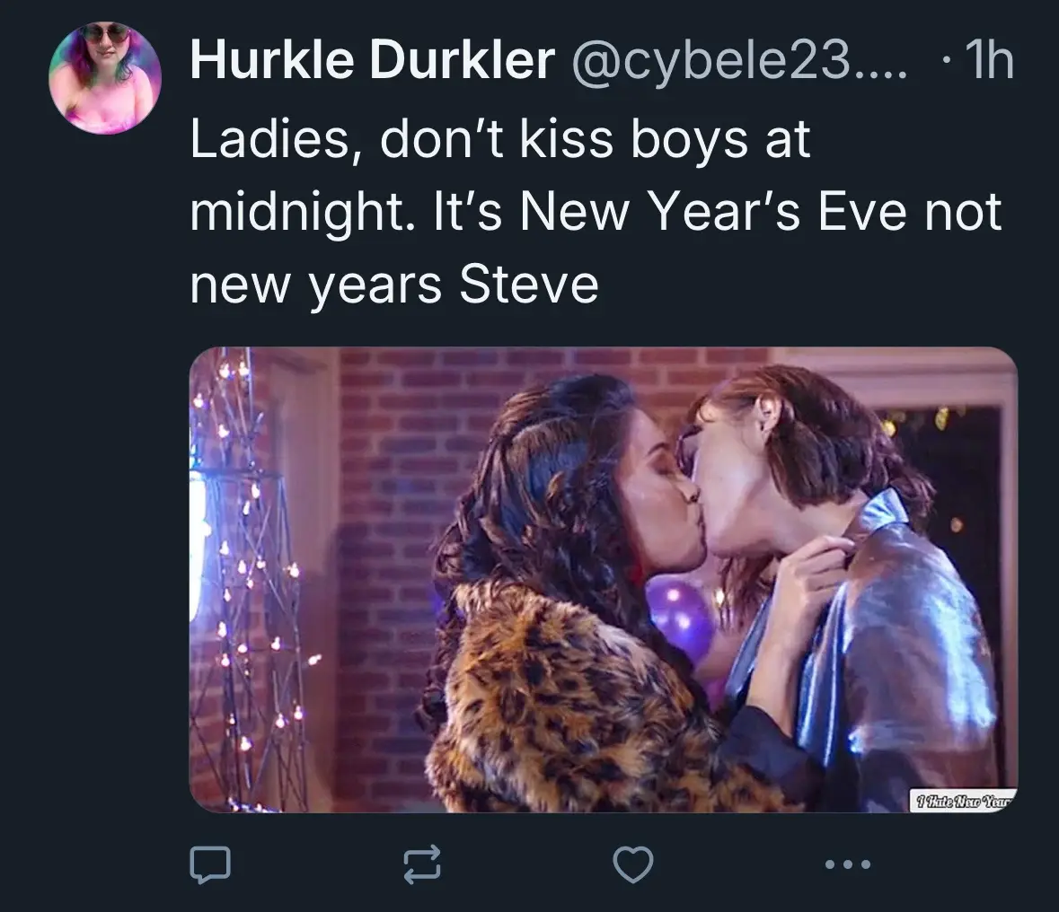 A screenshot of a tweet by Hurkle Durkler shows a photo of two women kissing passionately at what appears to be a New Year's…