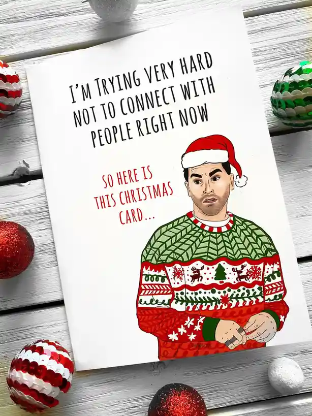 A Christmas card features a cartoon illustration of a man wearing a red Santa hat and a green and red ugly Christmas sweater…