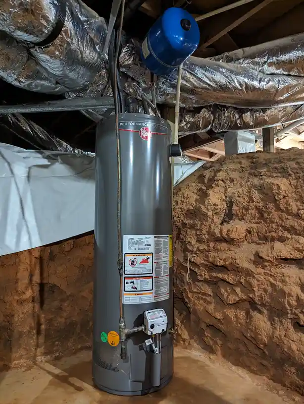 A gray Rheem Performance Platinum water heater stands in a basement with exposed dirt walls and ceiling ducts, with overlaid…