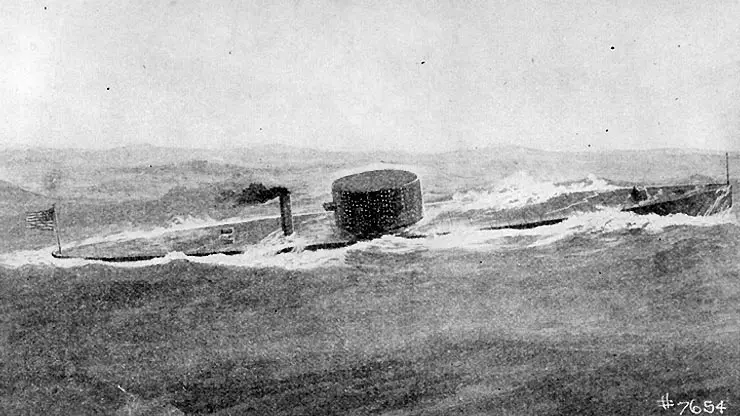 A black-and-white historical photograph shows a vintage submarine with a cylindrical conning tower and smokestack, partially…