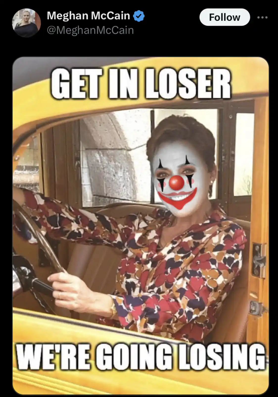 A woman with a clown face painted on her face is sitting in the driver's seat of a yellow vintage car, holding the steering…