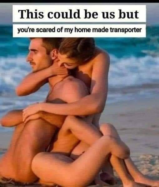 A couple is shown in an affectionate embrace on a beach, with the man sitting and the woman hugging him from behind. The…