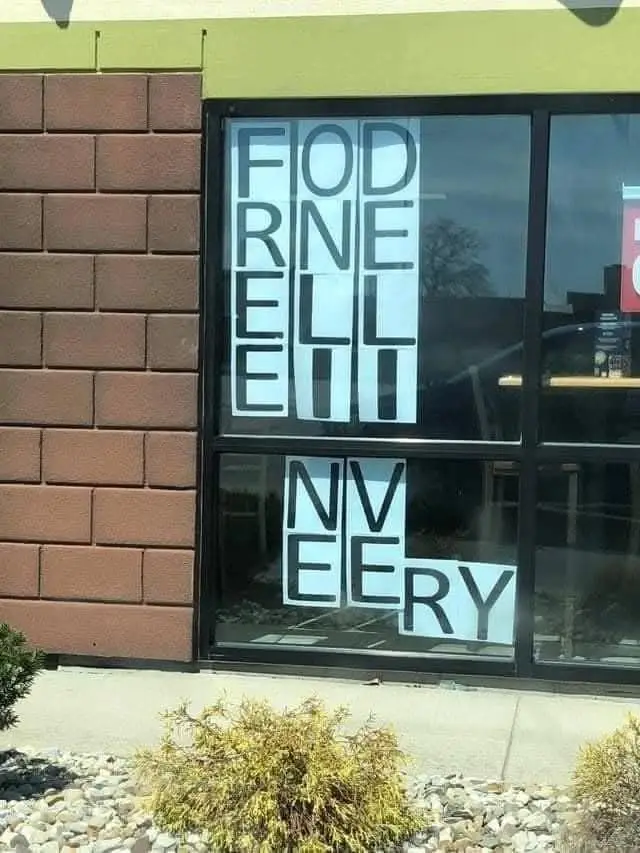 A storefront window displays large, white, cut-out letters arranged vertically and horizontally to spell 'FOD RNE ELL EII NV…