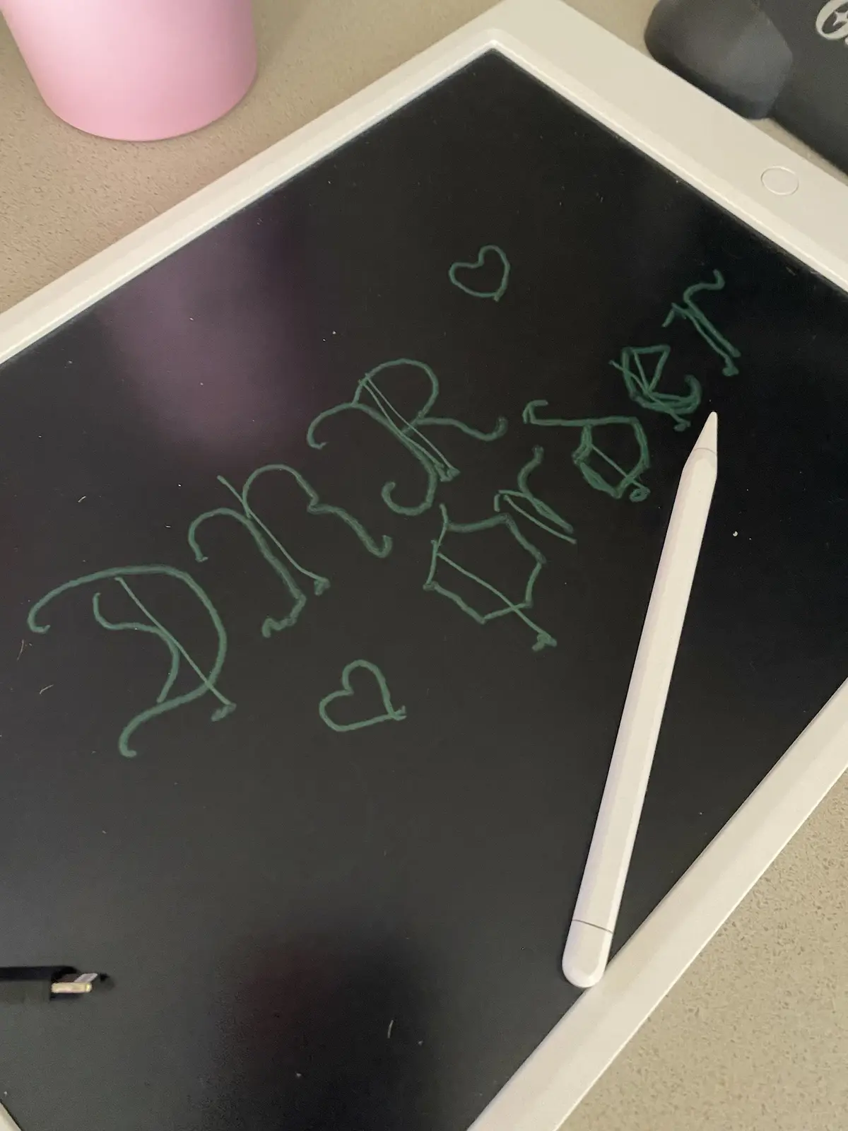 A white digital drawing tablet displays the word 'Dinner' written in green cursive script, flanked by two small hearts. A…