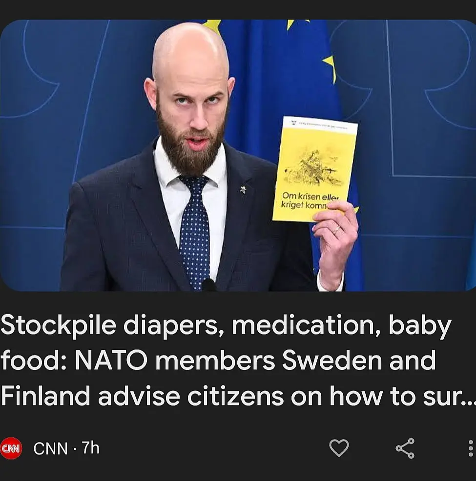 A bald man with a beard in a suit and tie holds up a yellow book titled 'Om krisen eller kriget komn' in front of a blue EU…