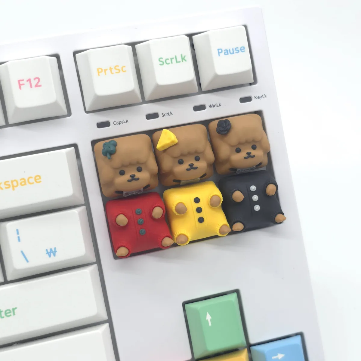 A close-up of a white computer keyboard with custom, cute, poodle-themed keycaps. The top row shows standard keys like…