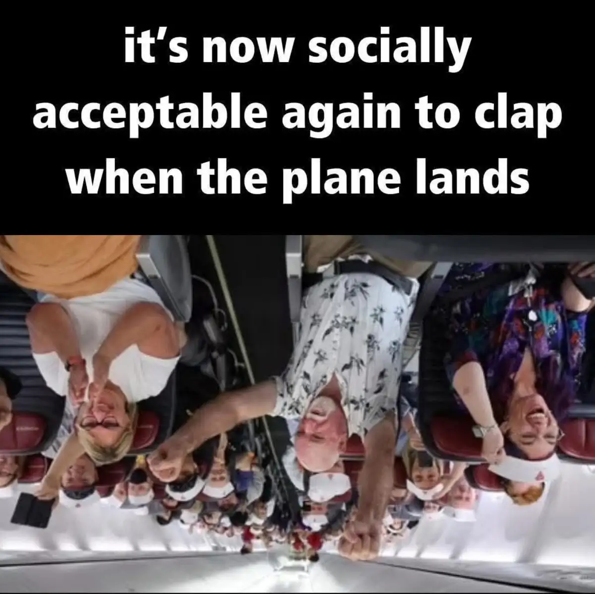 An upside-down photo of airplane passengers seated in rows, all clapping with joyful expressions. The overlaid text reads…