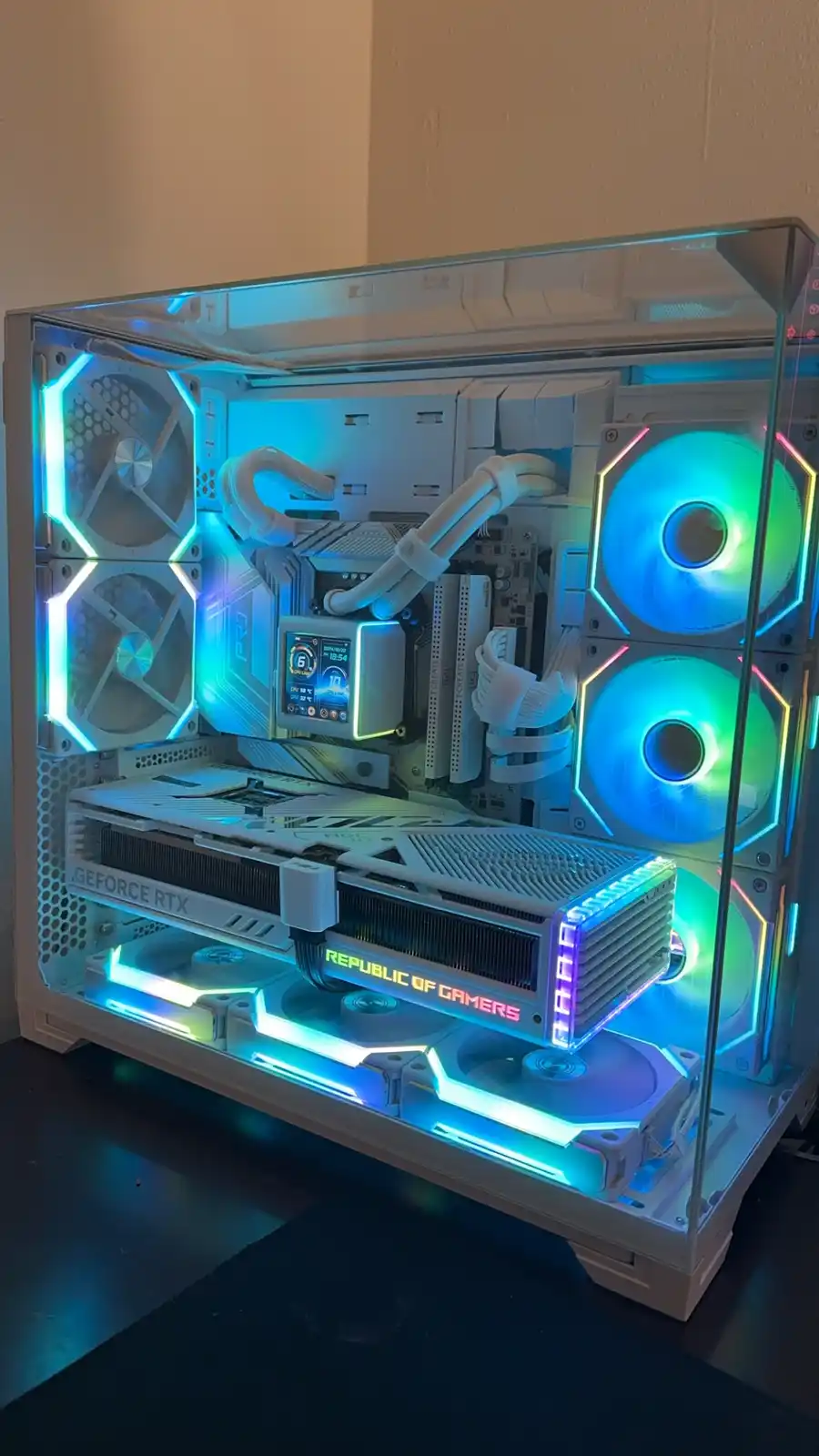 A white, transparent-sided gaming PC case with RGB lighting, showing a high-end GeForce RTX graphics card, multiple fans…