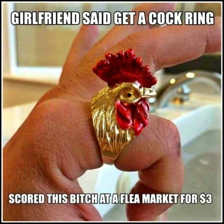 A hand holds up a large, ornate ring shaped like a rooster's head, featuring gold-colored metal and red enamel for the comb…