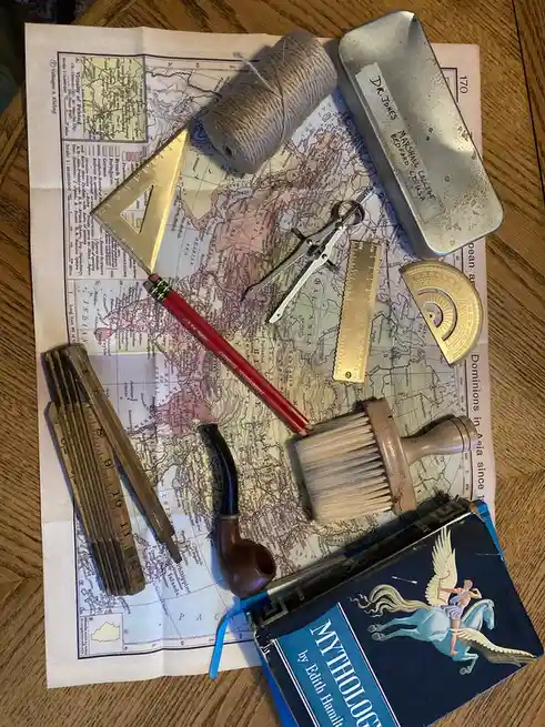 An overhead shot displays a vintage map of Asia and the Indian Ocean, overlaid with various old-fashioned tools including a…