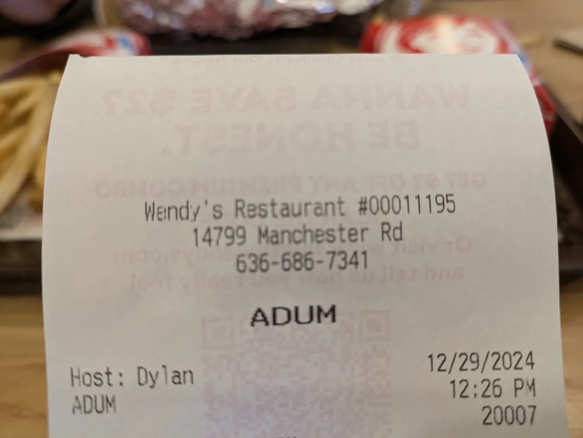 A close-up photo of a Wendy's receipt showing the restaurant's address and phone number, with the word 'ADUM' printed…