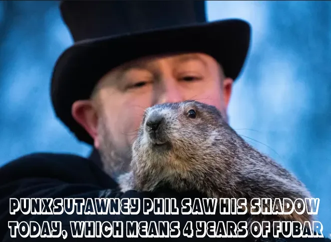A man in a black top hat holds a groundhog close to his face against a blurred blue background. White text overlaid at the…
