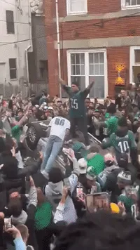 A sequence of six images shows a large, enthusiastic crowd of people in a narrow urban alleyway, many wearing green and…