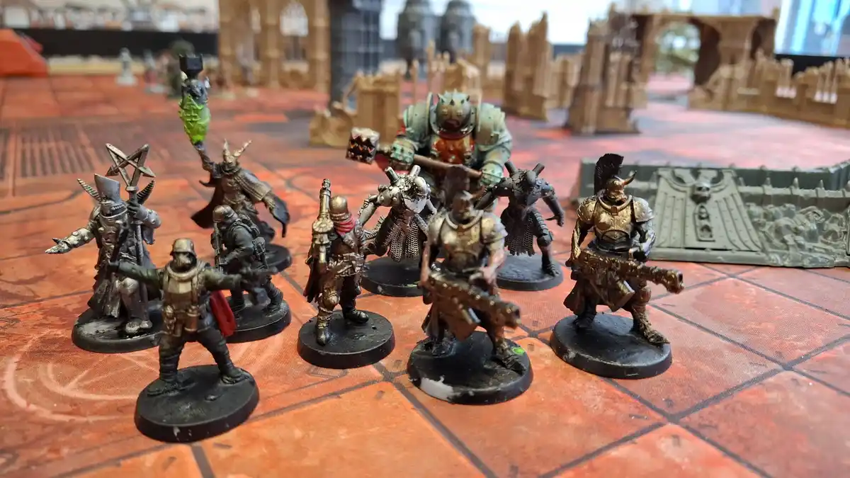 A group of painted miniature fantasy or sci-fi war game figures, including a large green-skinned beastman with a hammer, a…