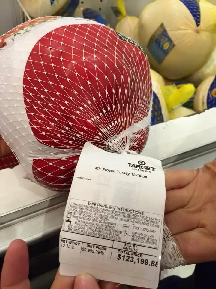 A person holds a frozen turkey in a red and white net bag with a Target price tag. The tag shows a unit price of $9.999.99…