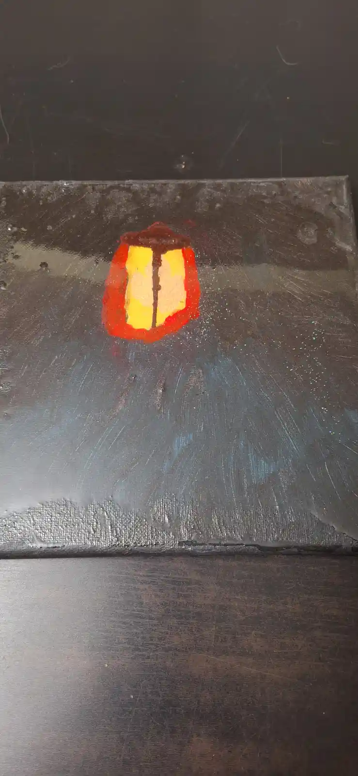 A small, hand-painted canvas depicts a glowing red lantern with a yellow light against a dark, textured background. The…