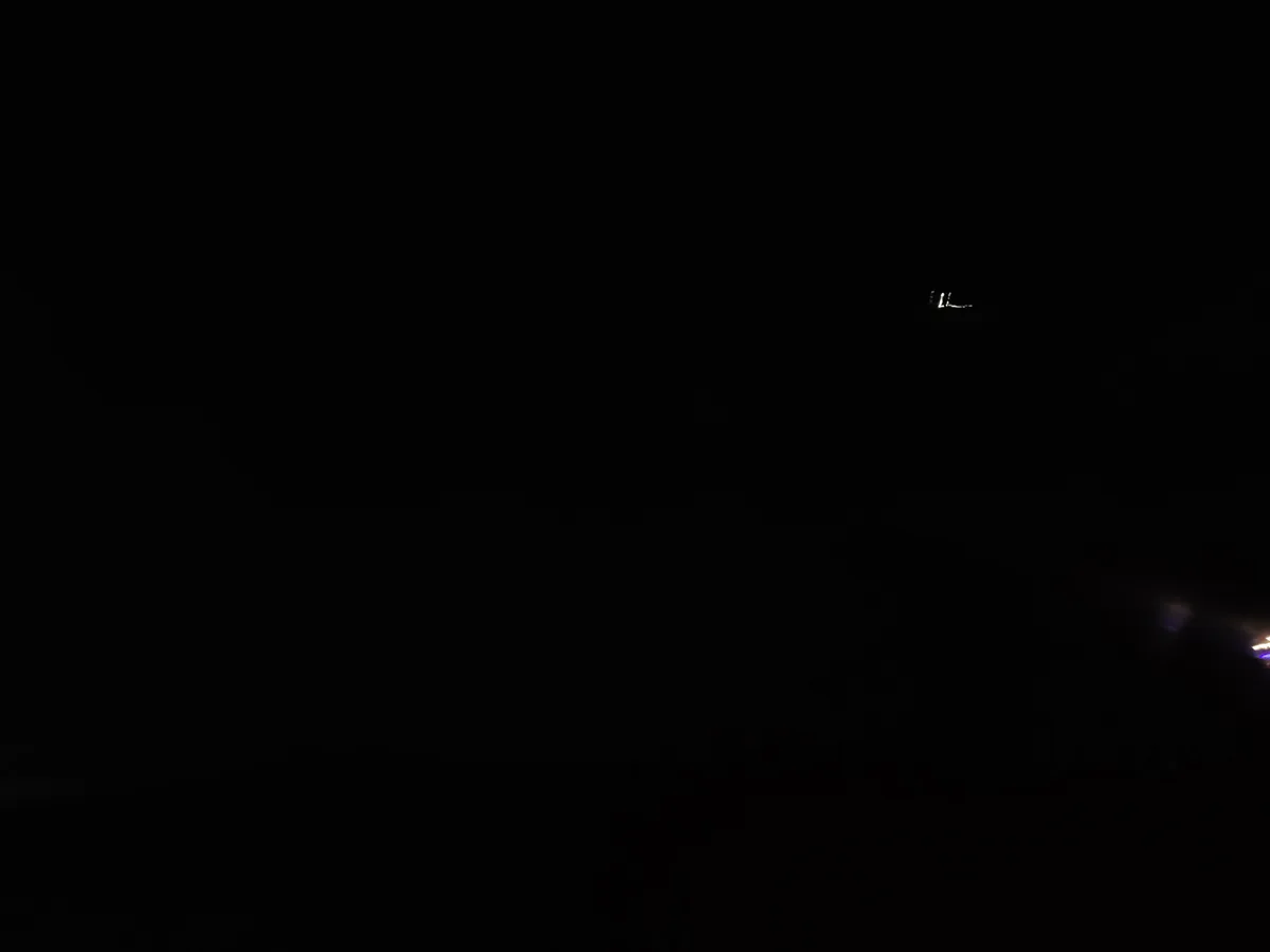 A nearly black image with faint lights visible in the distance, suggesting a dark environment at night. The overlaid text…