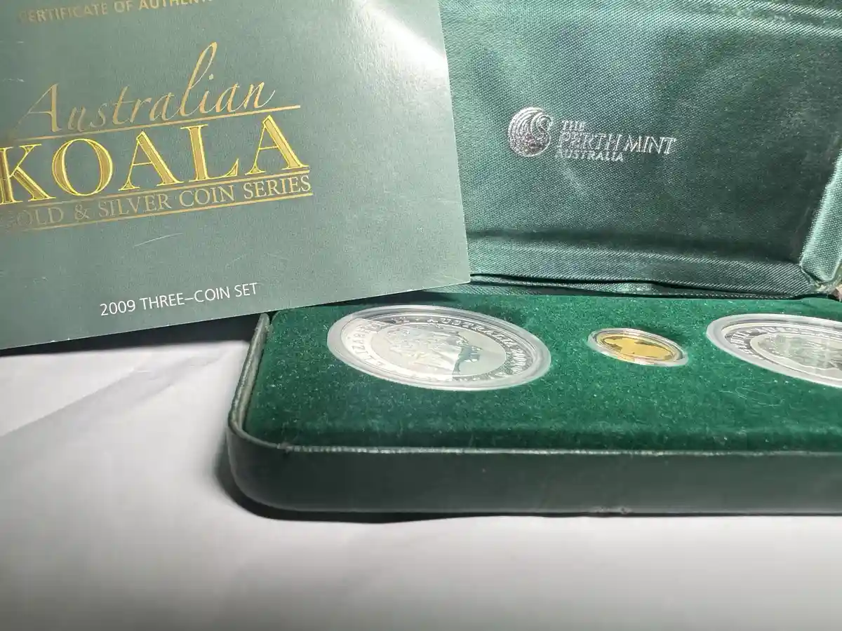 A close-up photo shows an open green velvet coin case from The Perth Mint Australia, containing three coins in protective…