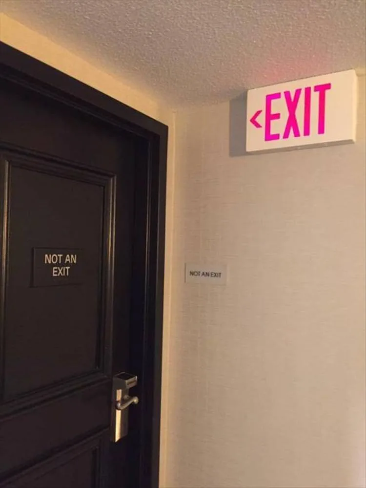 A dark door with a small plaque reading 'NOT AN EXIT' is shown next to a wall with a similar plaque and a bright pink…