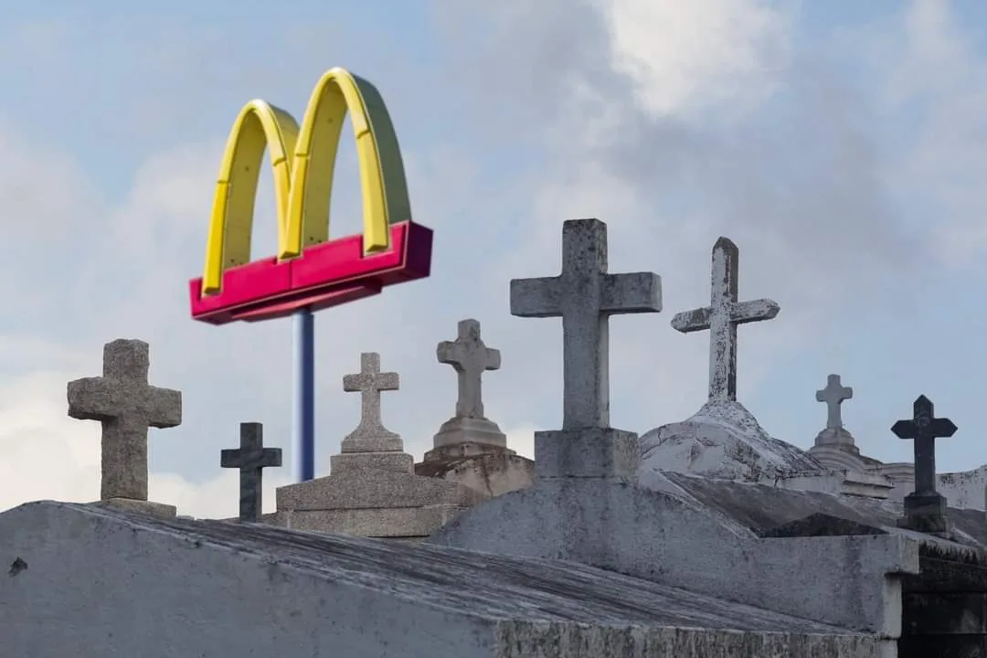A bright yellow and red McDonald's golden arches sign stands prominently against a cloudy sky, positioned directly above a…