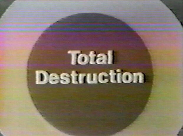 A grainy, VHS-style image shows a dark circular background with the words 'Total Destruction' in white 3D text. The entire…